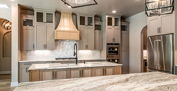 High-end custom kitchen featuring double wall ovens, custom range hood, oversized island, and elegant cabinetry in a Texas Hill Country home.