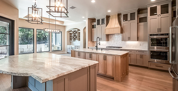 Gourmet kitchen with dual islands, custom wood cabinetry, quartz countertops, designer pendant lighting, and premium finishes in a Bulverde custom home.