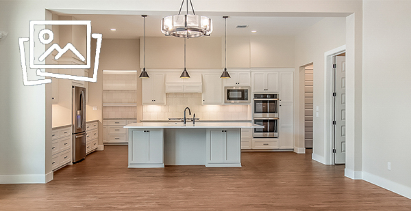 Luxury custom kitchen featuring a large quartz island, double ovens, custom cabinetry, and walk-in pantry