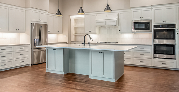 Chef’s kitchen with large center island, custom white cabinets, stainless steel appliances, and abundant storage