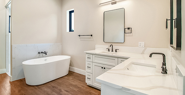 Spa-inspired primary bath featuring a freestanding tub, custom vanity cabinetry, quartz counters, and contemporary lighting
