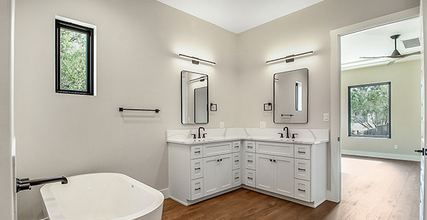 Luxury primary bathroom with freestanding soaking tub, dual vanity, quartz countertops, and black fixtures in a custom Boerne home